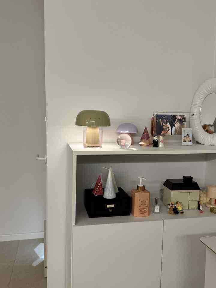 ホワイトとナチュラルカラーの寝室、ミニマルな棚にムードランプとキャンドルが配置された雰囲気のあるインテリア