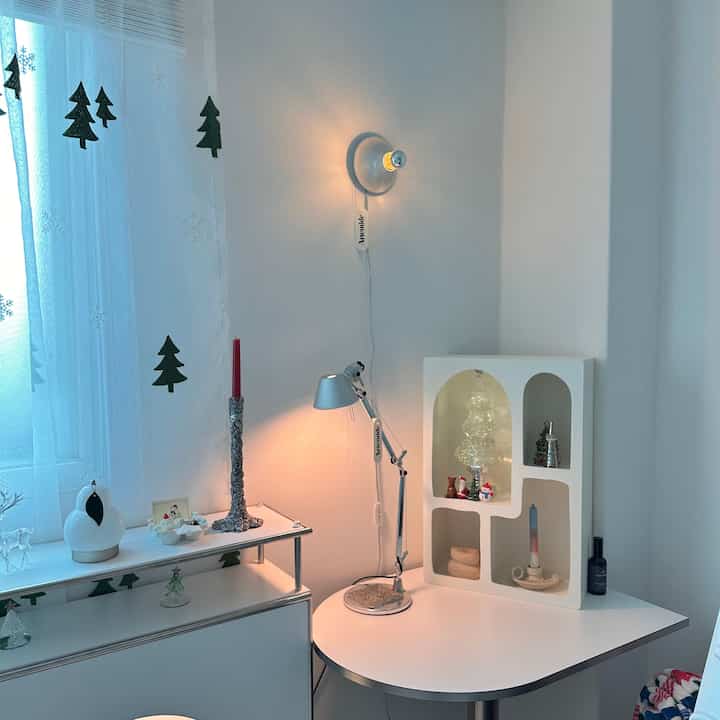 白とシルバーのトーンの狭い部屋、アーテミデのトロメオマイクロテーブルランプと壁照明が配置された印象的なミッドセンチュリーモダン空間