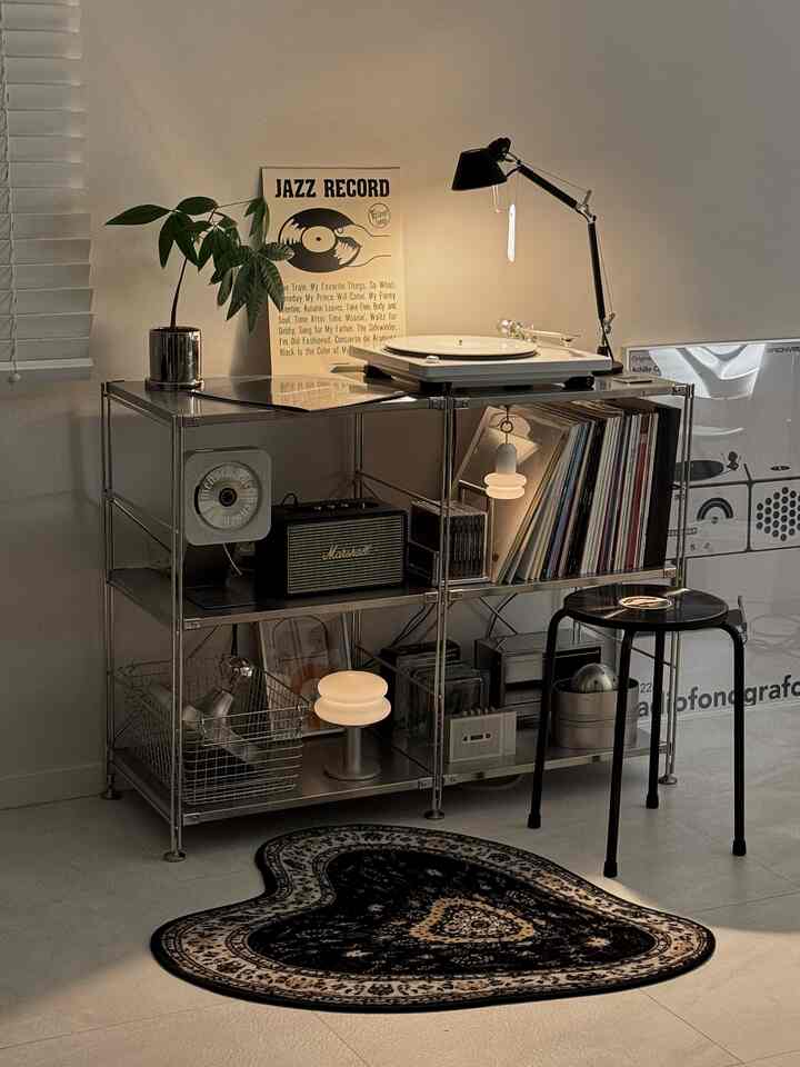 黒とアイボリーのムジスタイルのスチール棚に、ターンテーブルとスツール、ハート型ペルシャ絨毯が配置された音楽空間