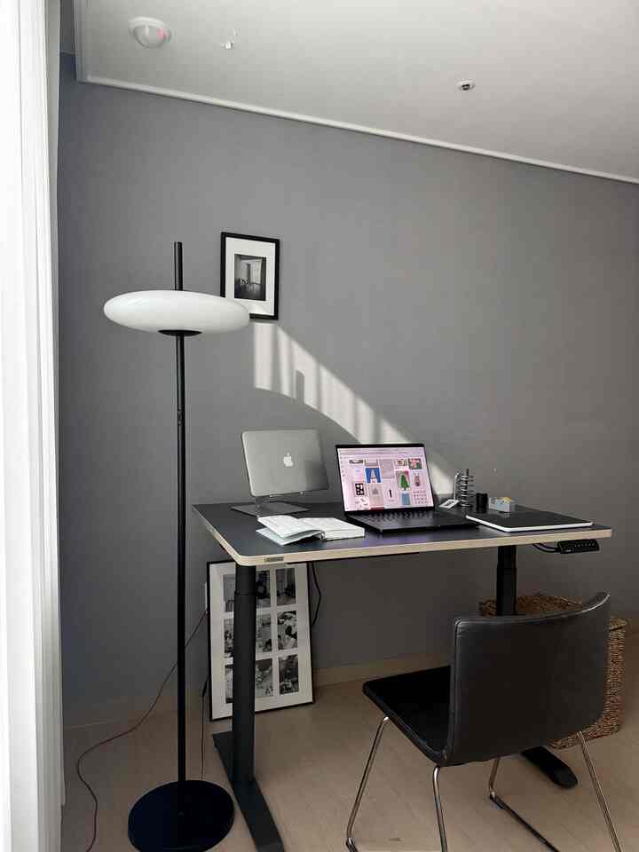 グレーの壁とモダンな黒いデスク、チェア、フロアランプが配置された清潔感のあるホームオフィスのインテリア