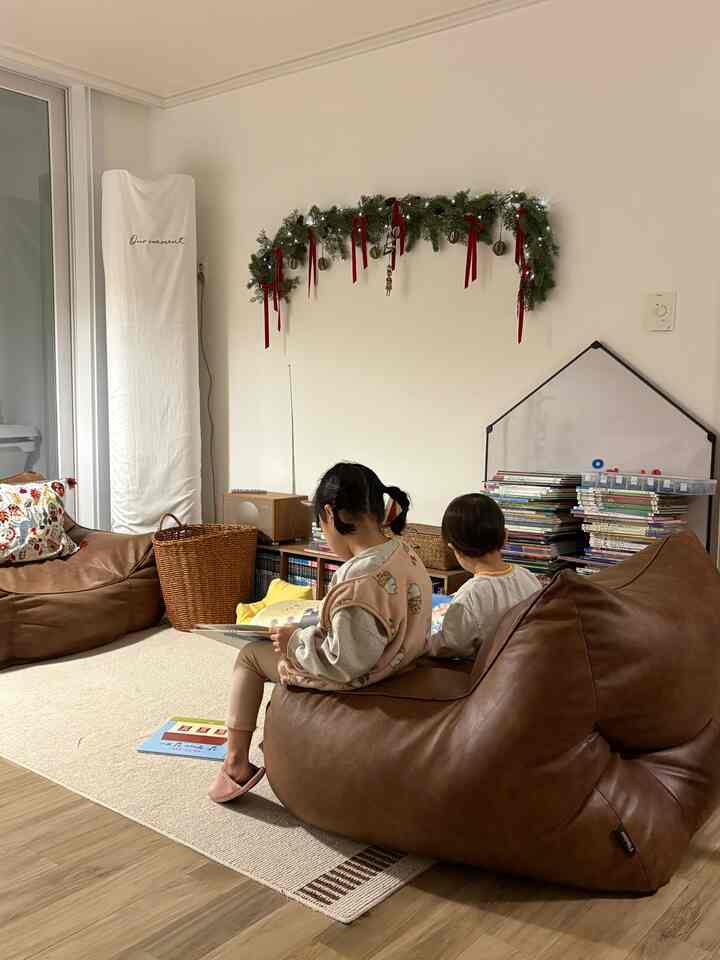 ブラウンのビーズクッションと子供たちが座るホワイトの壁とラグのある暖かい雰囲気のリビング