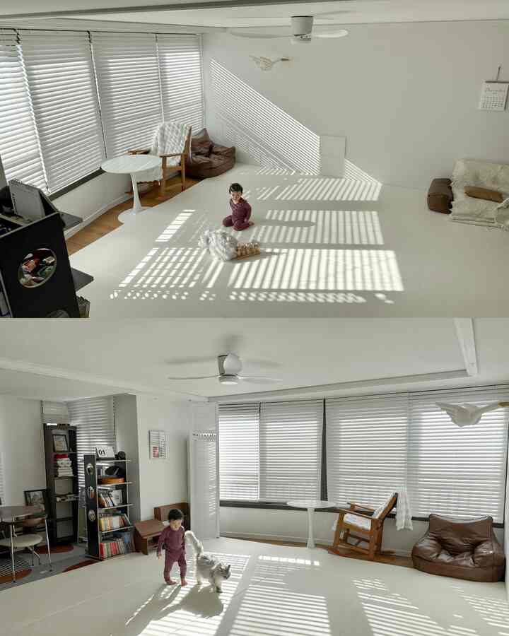 白を基調とした明るいリビングルーム、ブラウンの家具が調和し、子どもと猫が一緒に遊ぶ穏やかな空間