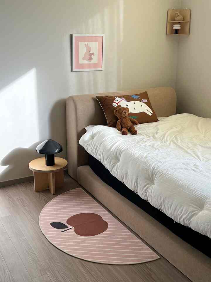 ナチュラルカラーの子供部屋、枕とベッド、ラグ、テーブルランプが配置された雰囲気のあるインテリア