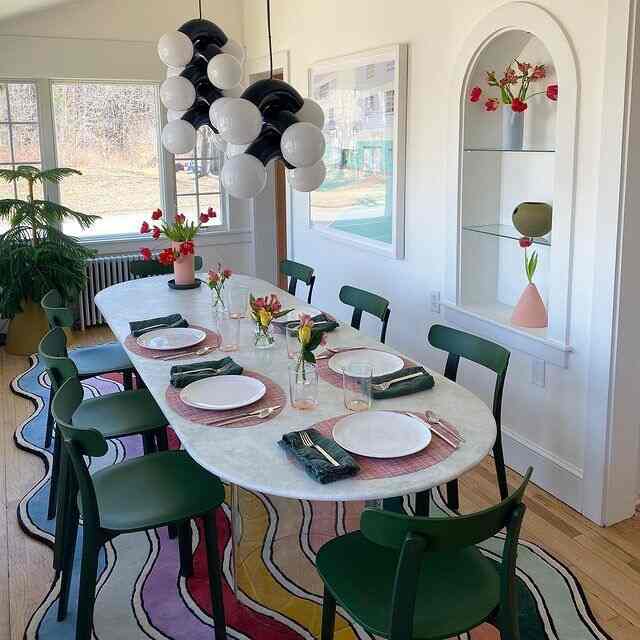 Green and white-toned dining room featuring green chairs and a white dining table with a simple modern atmosphere
