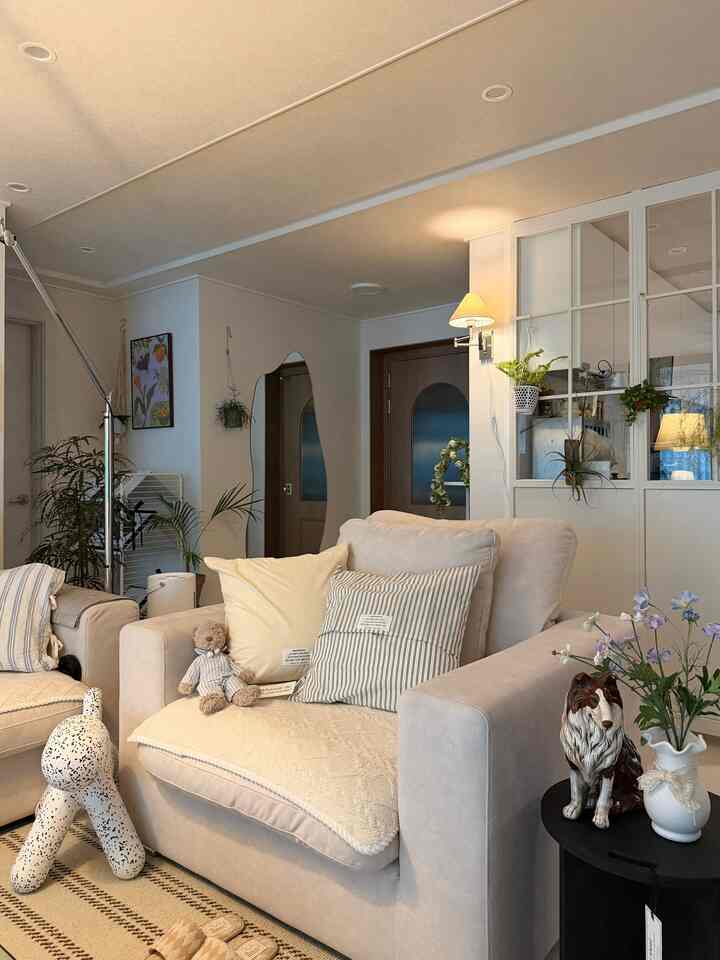 ベージュとナチュラルな色調のリビング、柔らかいクッションとソファが配置された雰囲気ある空間