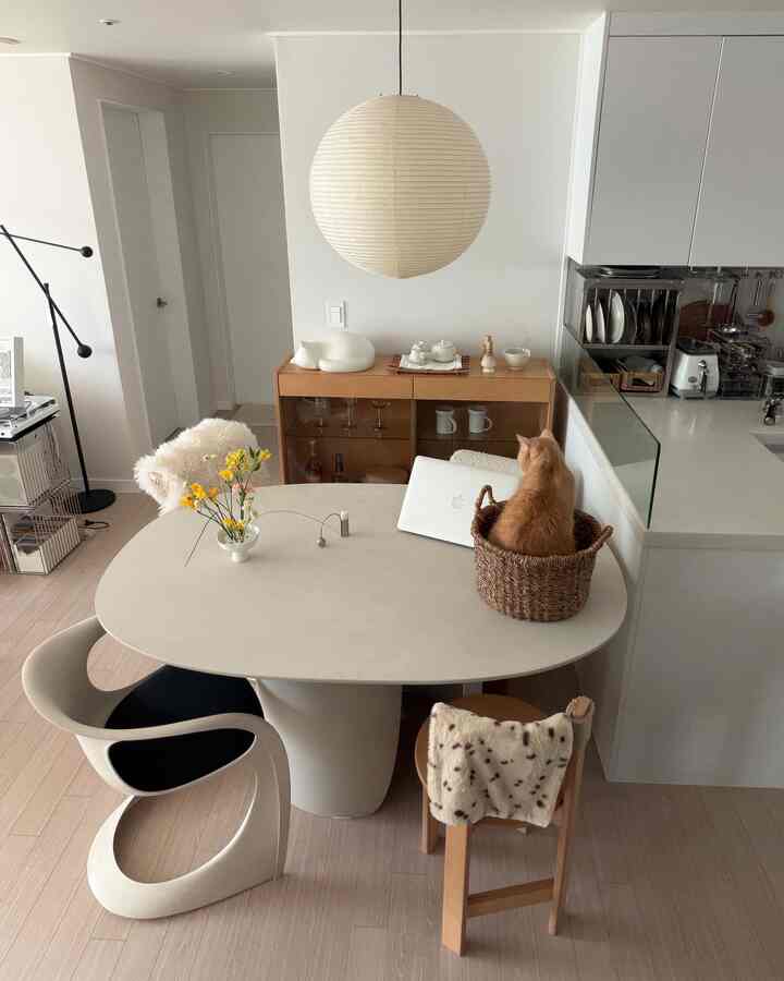 アイボリーとベージュのトーンのキッチン・ダイニング空間、オレンジの猫が座る落ち着いたナチュラルモダンなインテリア