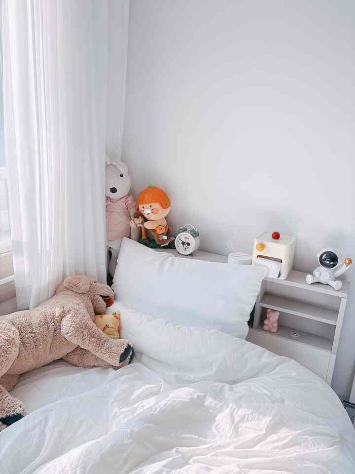 ホワイトトーンの子供部屋の寝室、ふわふわのぬいぐるみと白い寝具が配置された雰囲気のある空間