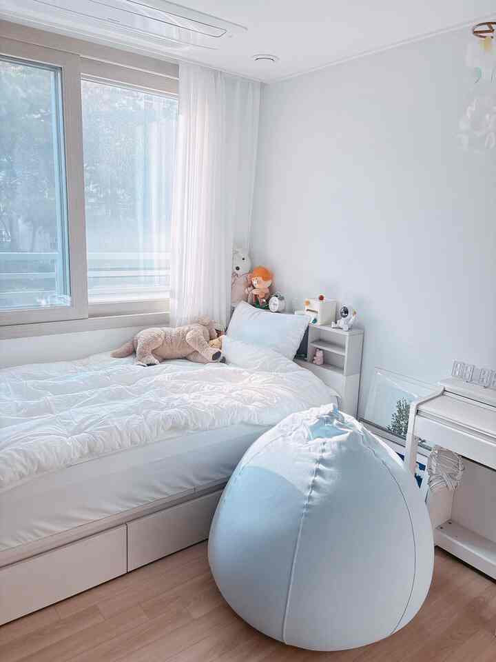 ホワイトトーンの子供部屋、収納付きベッドとビーズクッションが配置された明るく居心地の良い空間
