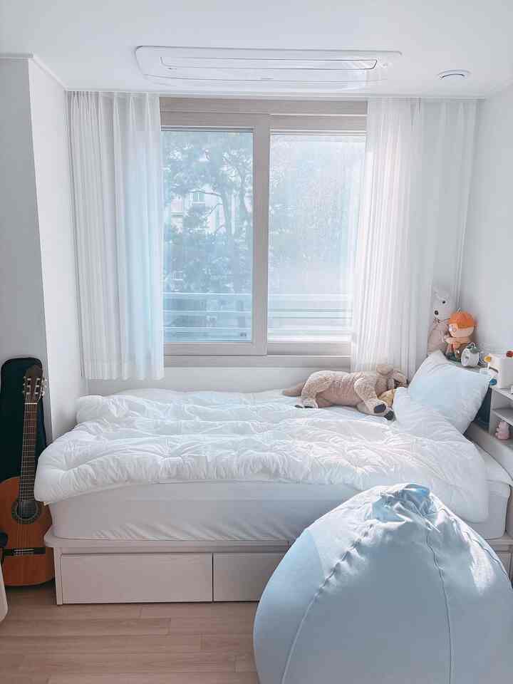 ホワイトとライトブルーの色調の子供部屋、収納付きベッドとビーンバッグソファが配置された明るく温かみのあるインテリア