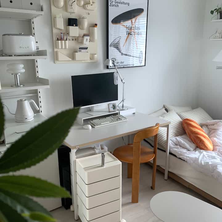 White and natural-toned studio apartment combining home office and bedroom