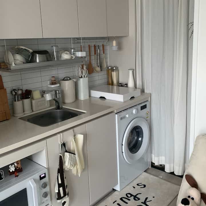 Small kitchen space in white tones featuring sink and neatly arranged kitchen utensils