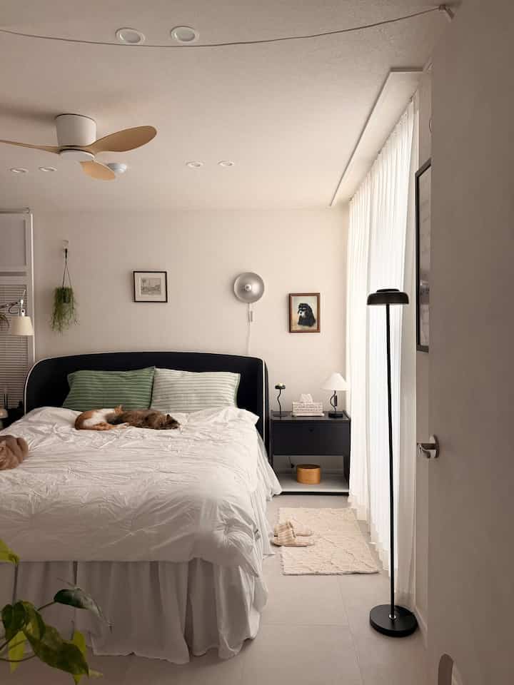 ホワイトとブラックのトーンが調和した寝室、大きなベッドとナイトテーブルが配された落ち着いた空間