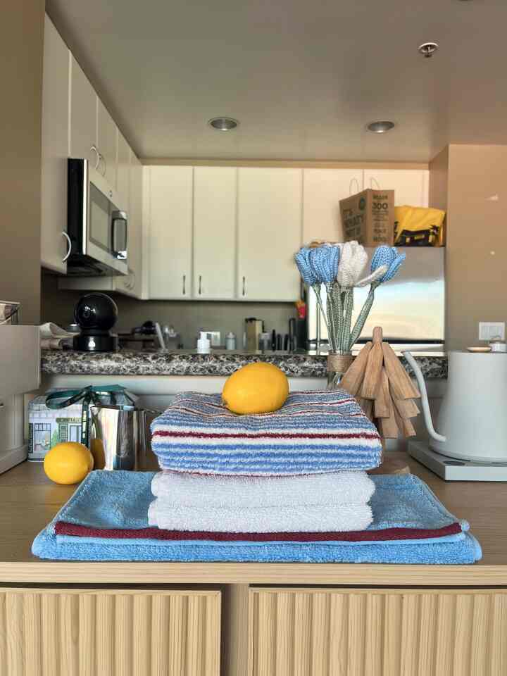 Beige and wood tone kitchen space featuring stacked blue and white towels with lemons, creating a simple home cafe atmosphere