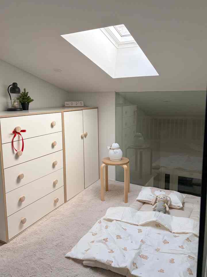 ホワイトとベージュのトーンのロフト子供部屋で、低い天井と収納が配置された温かみのあるインテリア