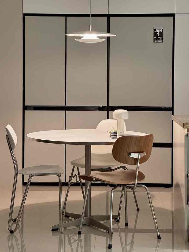 白とシルバーのトーンのダイニングスペース、ラウンドテーブルと異なる椅子が調和したシンプルでモダンなインテリア