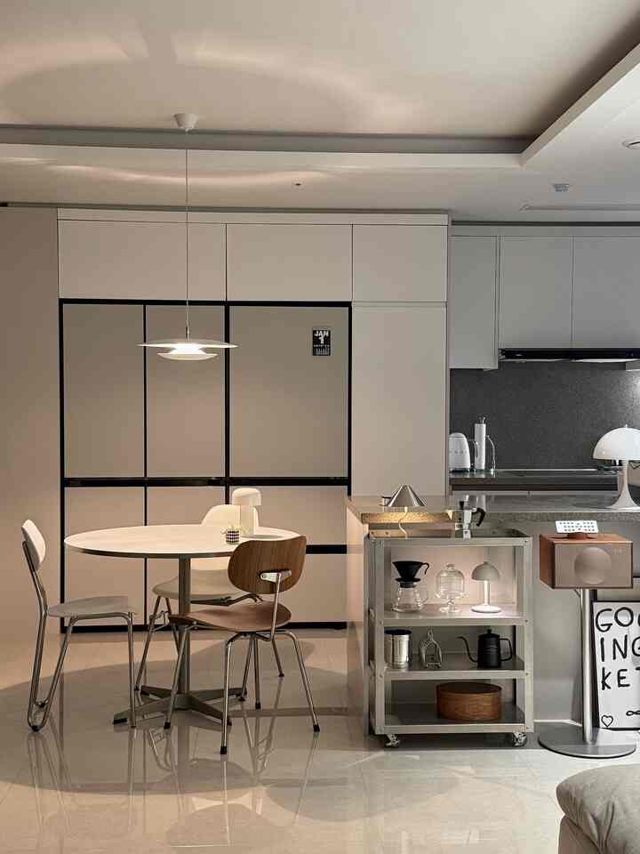 白とベージュを基調としたキッチン空間、丸いテーブルとモダンな照明や家具が配置された洗練された雰囲気のインテリア