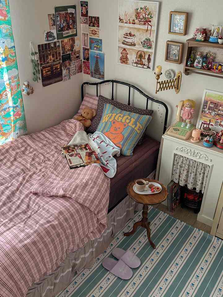 ピンク色調の寝室、チェック柄の寝具とヴィンテージ装飾が配された雰囲気のあるインテリア