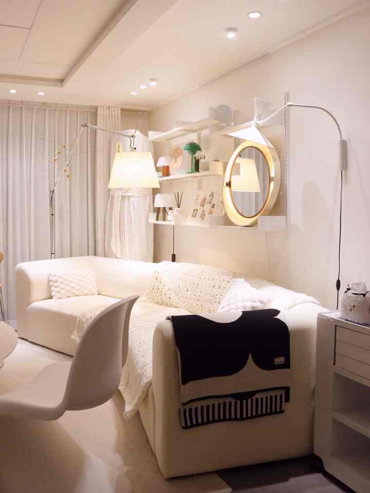 温かみのあるホワイトとナチュラルトーンのリビング、コーナーソファと多様な照明が調和した雰囲気のあるインテリア