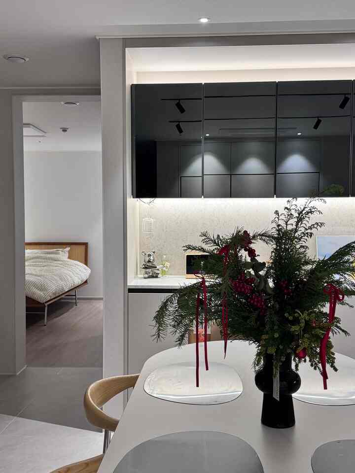 ナチュラルな色調のキッチンスペース、白いテーブルに花瓶とランチョンマットが置かれた、シンプルで温かみのあるインテリア。