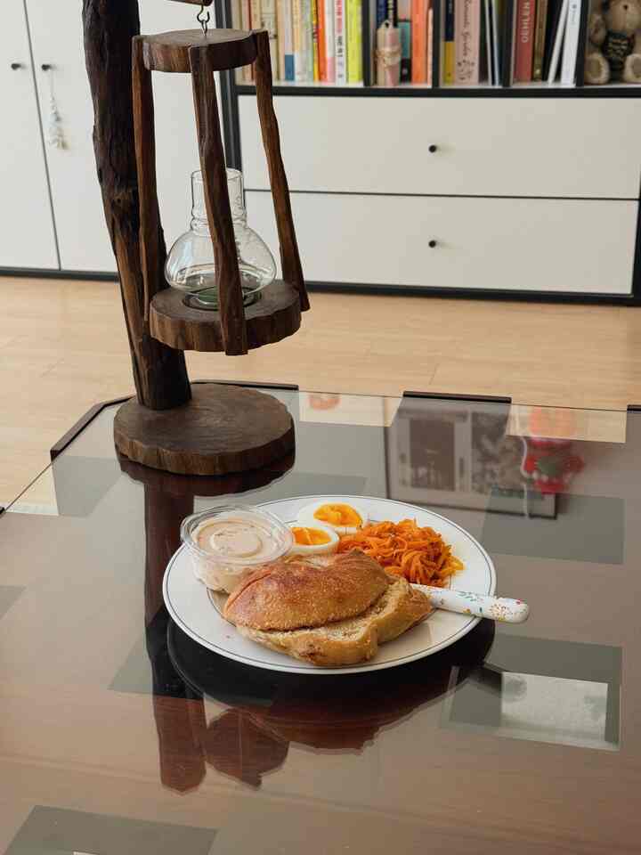 木目調のナチュラルなリビング、ガラストップのコーヒーテーブルにブランチの皿が置かれた雰囲気のある空間