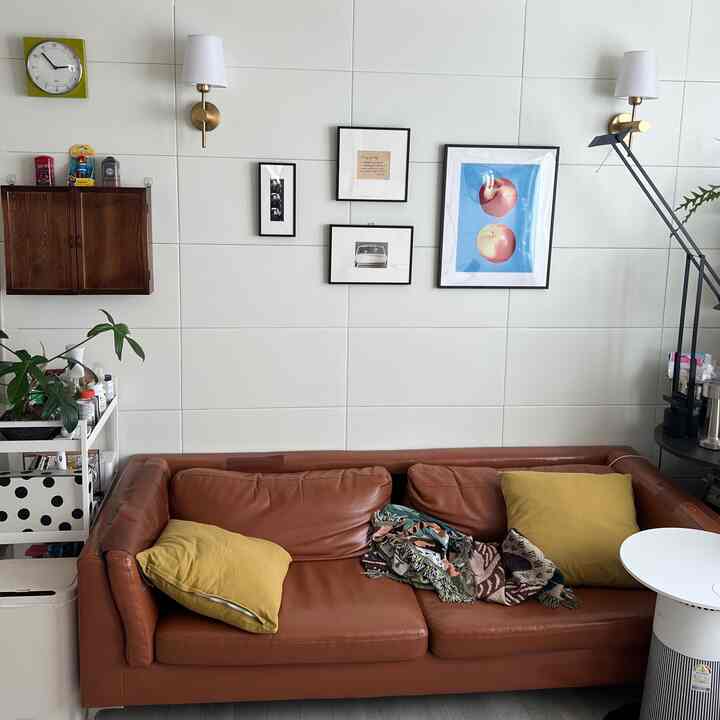 白いタイル壁とブラウンのレザーソファがある二人暮らし向けのリビング、ヴィンテージ感とおうちカフェの要素が調和したインテリア