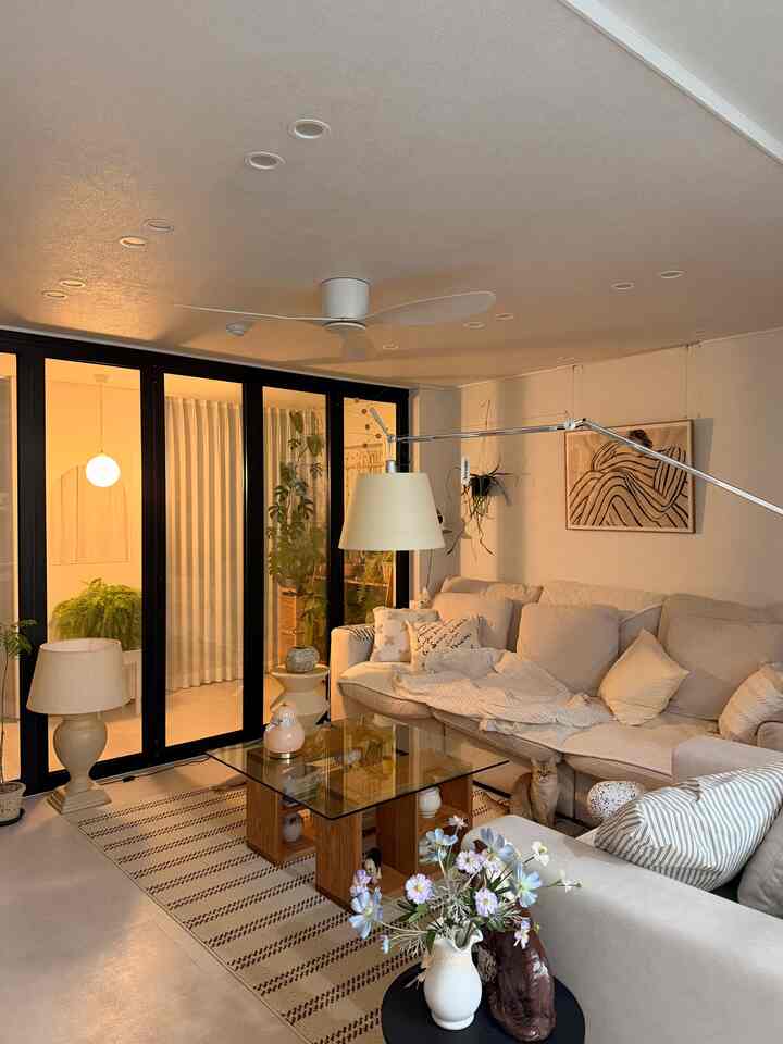 ベージュトーンのリビングルーム、4人掛けソファとガラスのコーヒーテーブルが配置された雰囲気のあるインテリア