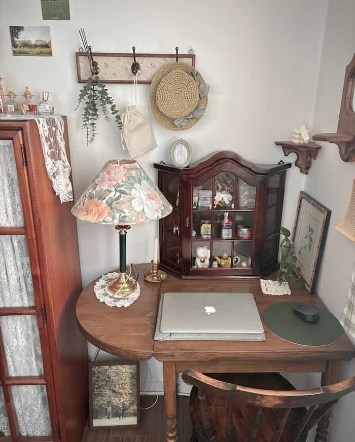 ブラウンの木目調とナチュラルカラーのホームオフィス、アンティークなデスクと花柄ランプが配置された落ち着いた雰囲気のインテリア