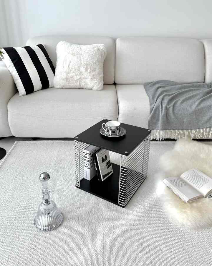 モノトーンの白を基調としたリビング、ミニマルなソファとブラックシルバーのサイドテーブルが調和した印象的な空間