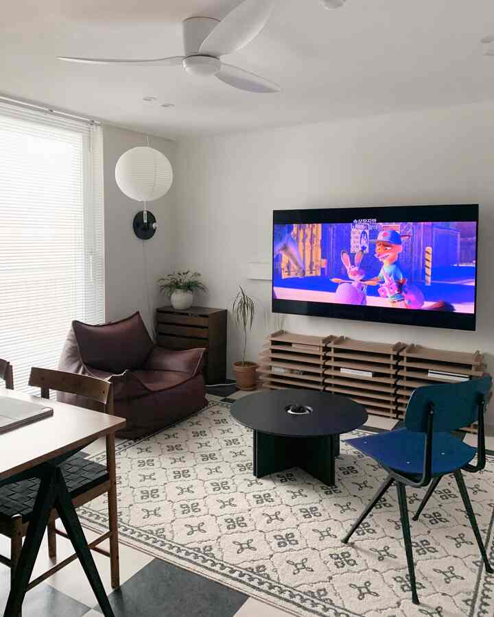 White and beige toned living room featuring brown bean bag sofa and round black coffee table with cozy ambiance