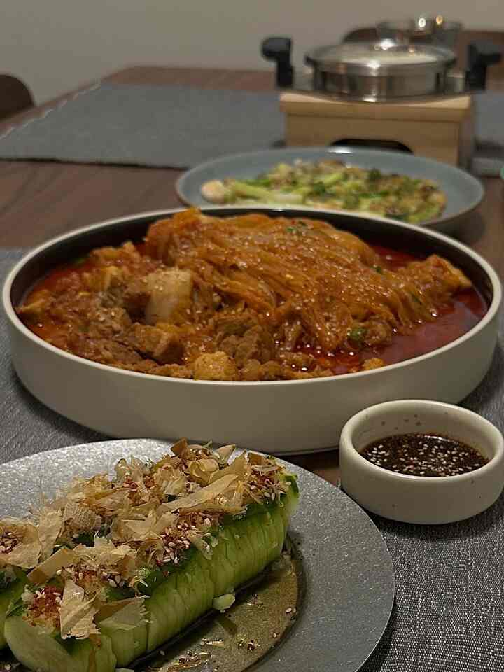 Brown wood-toned dining room featuring a table set with kimchi stew and side dishes creating a cozy dinner vibe.
