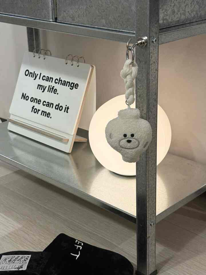 銀色の亜鉛メッキ棚にムードライトと名言カード、ぬいぐるみのクマの飾りが置かれたシンプルなインテリアディテール