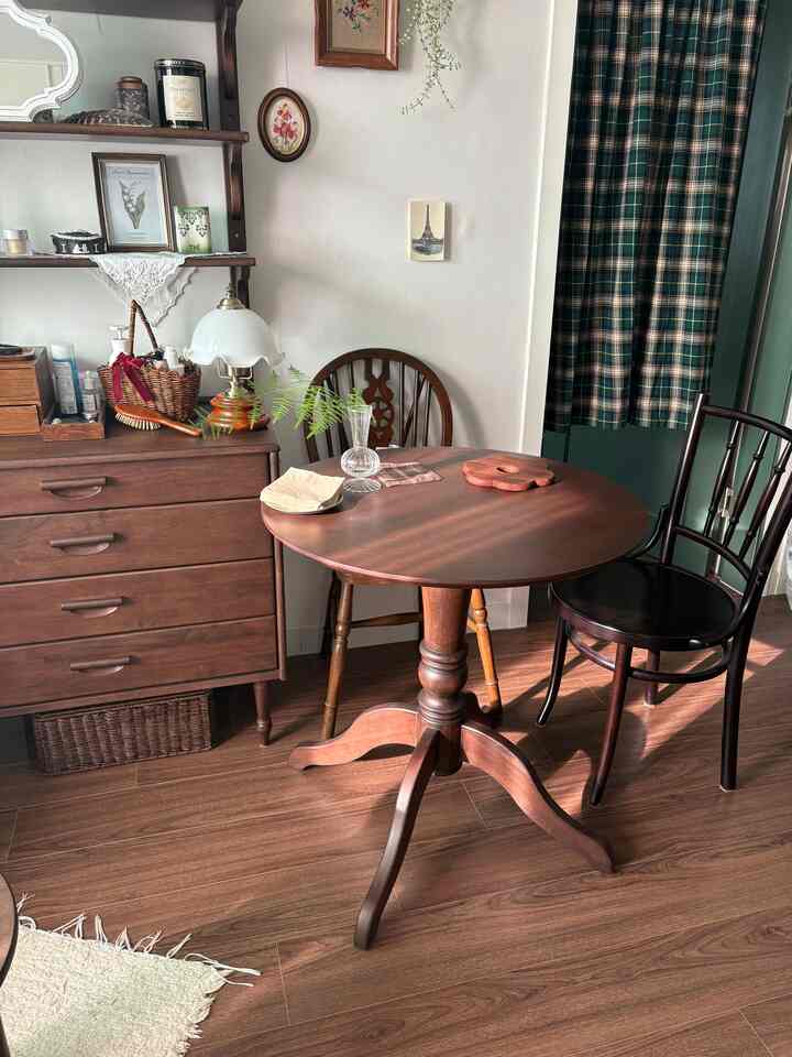 ナチュラルな木目調とヴィンテージ家具が調和したリビング・ダイニング空間、木製の丸テーブルとクラシックな棚が配置された落ち着いた雰囲気のインテリア