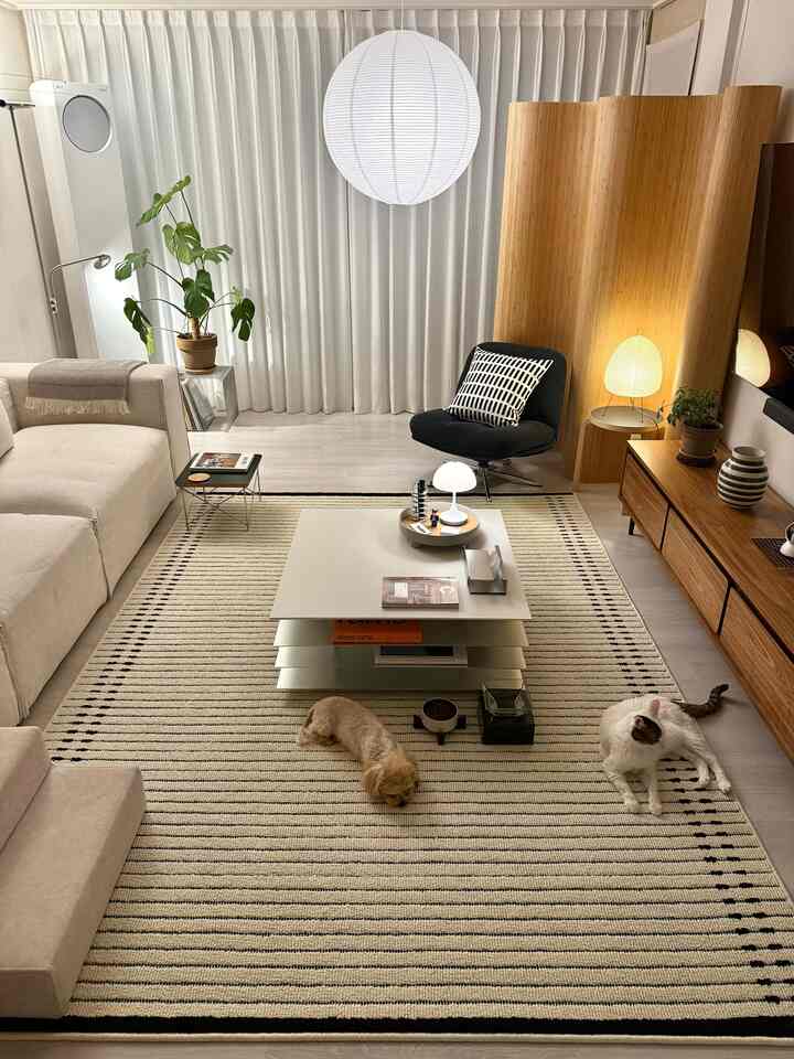 ベージュと木目調の調和があるリビング、ソファとコーヒーテーブル、ラグの上に犬と猫がくつろいでいる雰囲気のあるインテリア