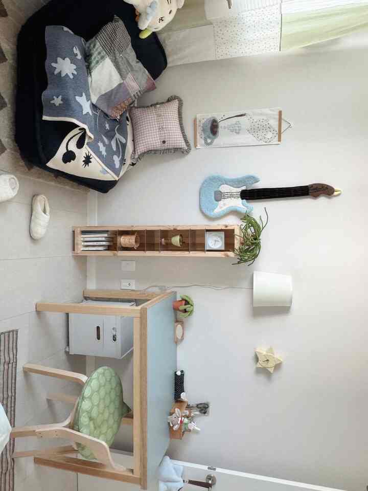 白とライトウッドトーンの小さな一人部屋、ソファと机、壁飾りが配置された雰囲気のある空間