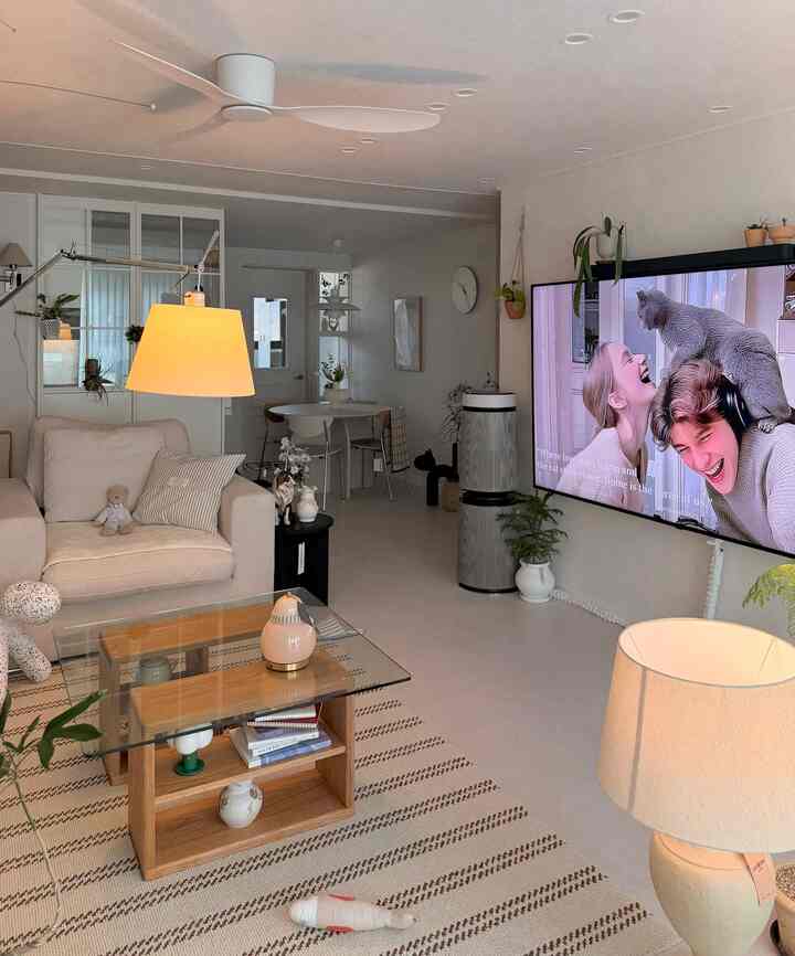 明るいホワイトとベージュのトーンのリビング、クリーム色のソファと木製のガラステーブルが配置されたモダンなヴィンテージスタイルの空間