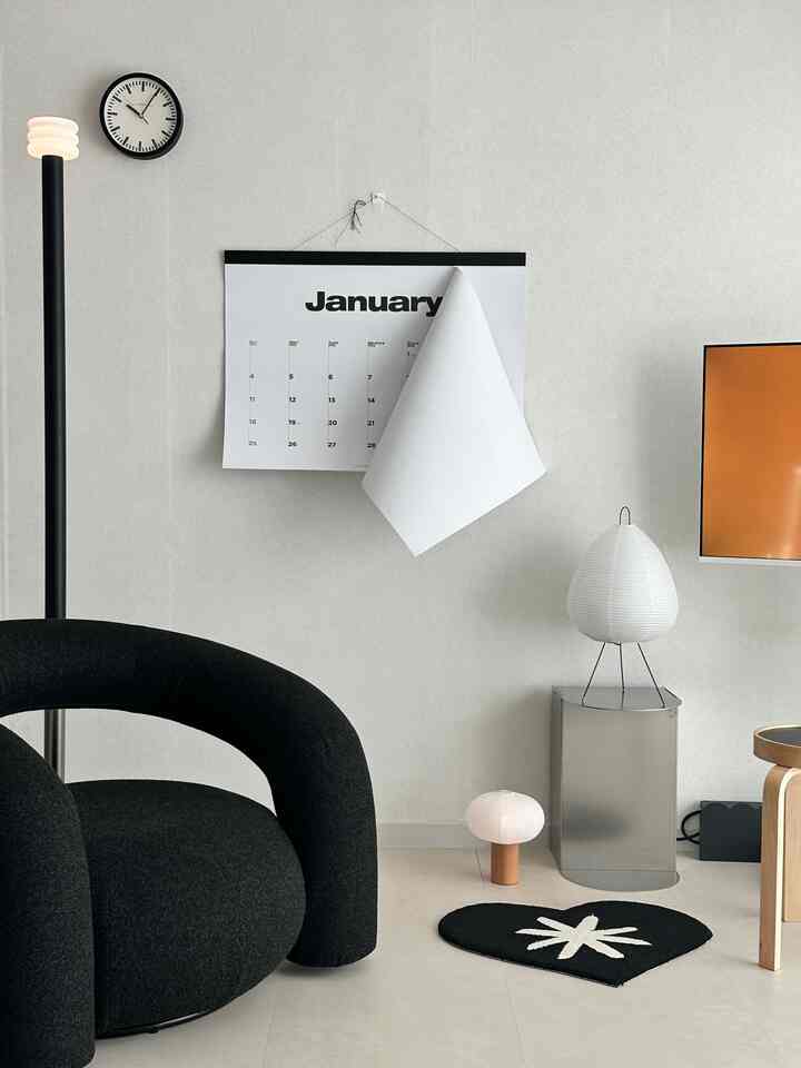 Monotone base living room featuring a black single sofa and a wall calendar with a minimalist and stylish atmosphere