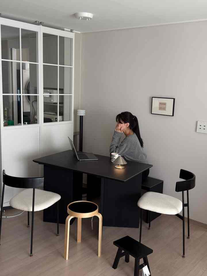 チャコールとホワイトのトーンのダイニングルーム、黒いダイニングテーブルとスツールが配置されたモダンでシンプルな雰囲気のあるインテリア