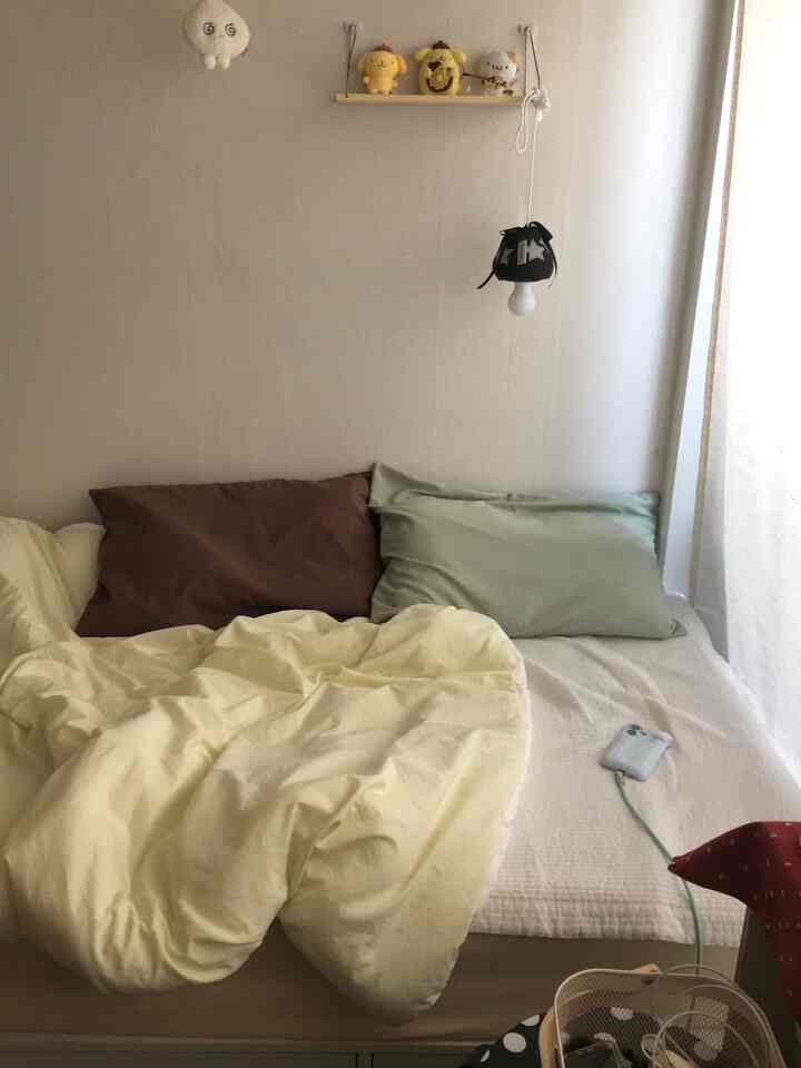 アイボリーとベージュの温かみのある寝室、ブラウンとミントの枕、柔らかな掛け布団カバーが配置された雰囲気のあるインテリア