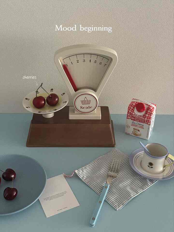 パステルトーンのキッチンテーブルにチェリーのオブジェや様々なキッチン用品が配された雰囲気のあるインテリア