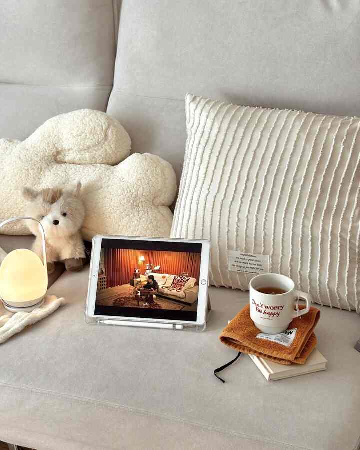 Ivory and light gray toned sofa featuring cushions, pet bed, and table lamp creating a cozy simple modern space