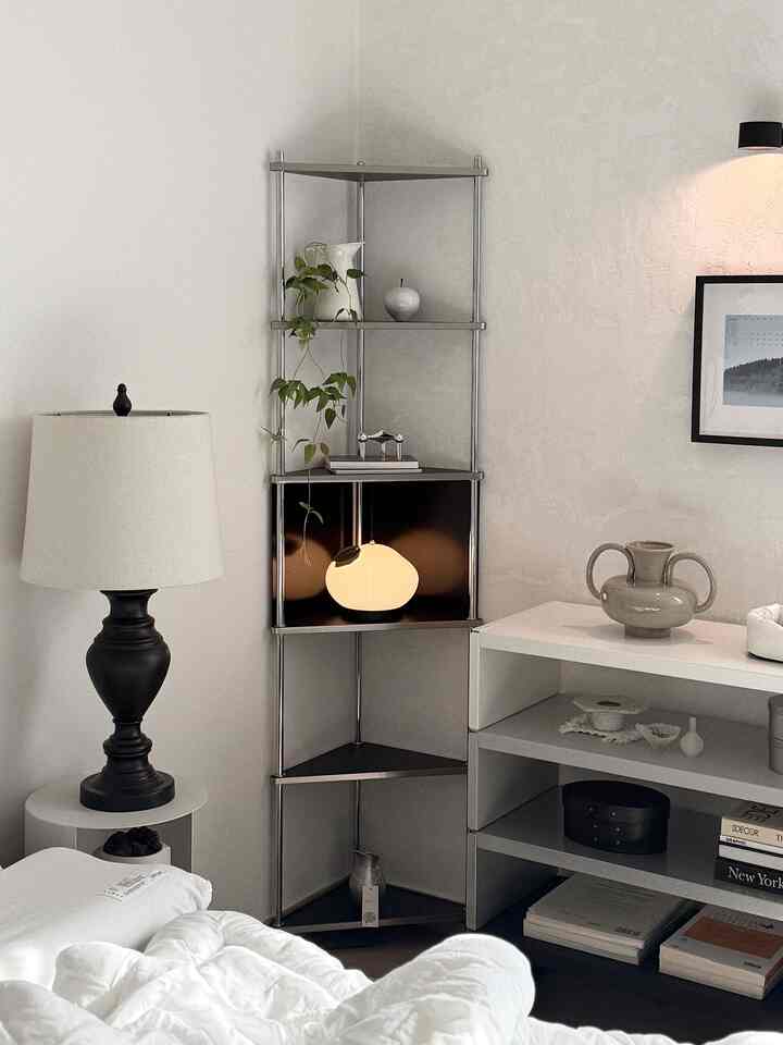 白と黒を基調とした寝室、コーナー収納棚とテーブルランプが配されたモダンで落ち着いたインテリア