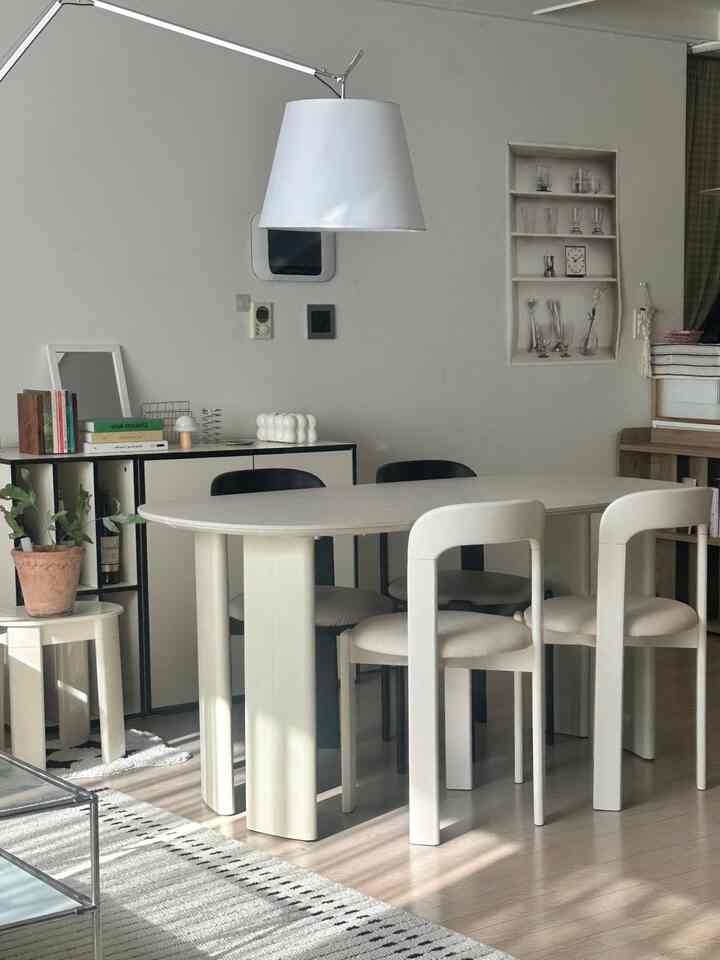 White and beige natural toned living room featuring a central dining table and chairs, creating a simple and modern atmosphere