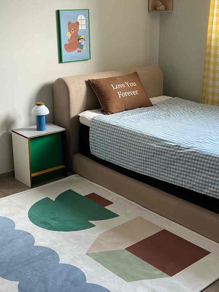 ベージュとブルーの色調の子供部屋、枕とかわいいポスターが配置された落ち着いた雰囲気のインテリア