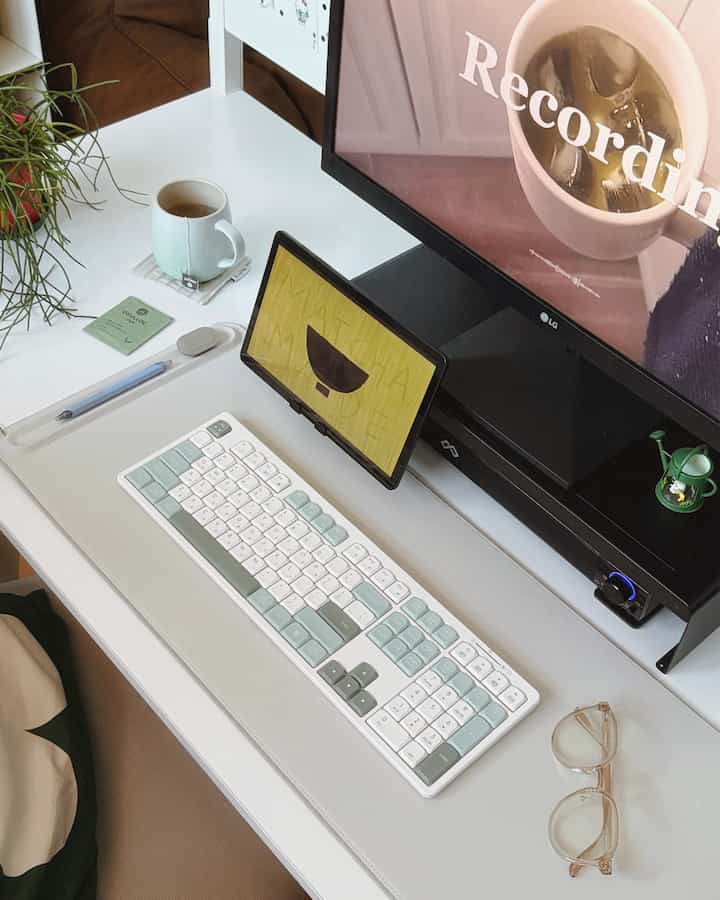 白と緑の色調のホームオフィス、モニターとタブレット、キーボードが配置されたコンパクトな作業スペース