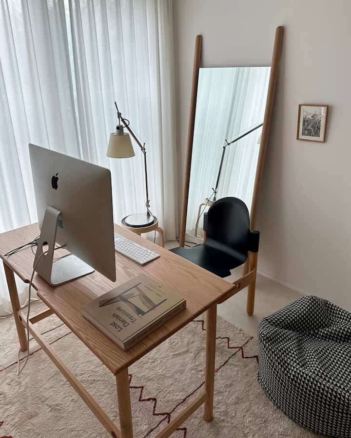 木目調のナチュラルなコンパクトなホームオフィス、木製デスクとチェア、全身鏡、トロメオのテーブルランプが配置された落ち着いた空間