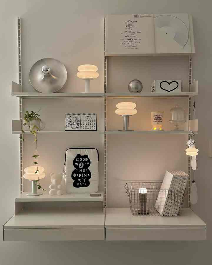 ホワイトとシルバーのトーンでまとめられたコンパクトな壁面シェルフ、ムードライトとステンレスワイヤーバスケットが配置されたミニマルで整理された空間