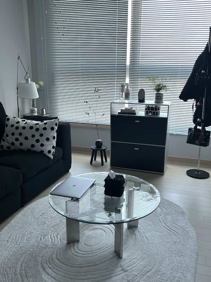 Monotone living room featuring a black sofa and glass coffee table with a minimalist and clean interior design