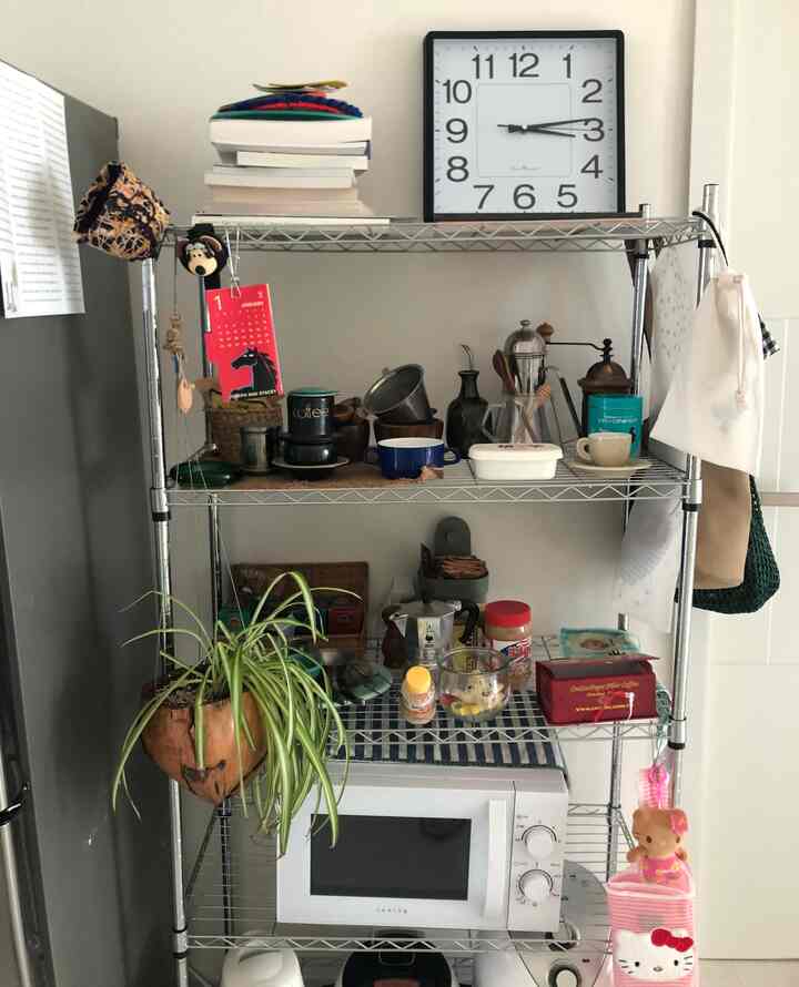 Bright gray-toned wall featuring industrial metal racks neatly organized with kitchen utensils and coffee accessories in a clean kitchen space