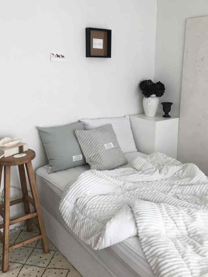 White and beige toned living room featuring simple natural style sofa with cushions, creating a calm minimalist atmosphere