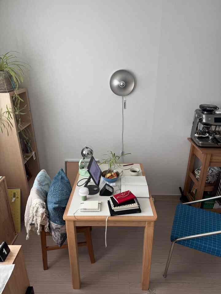 ナチュラルな色調のホームオフィス、木製のデスクと本棚、コーヒー機器が配置された雰囲気のある作業空間